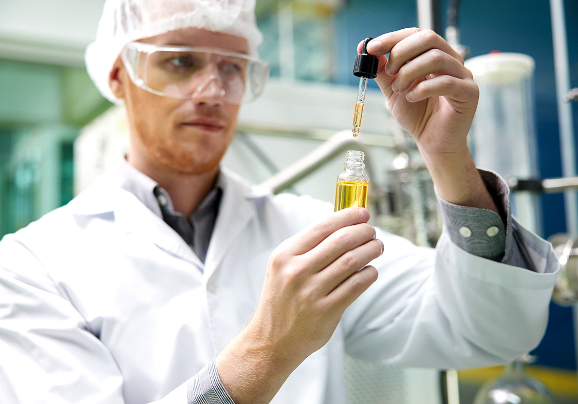 scientist testing and holding cannabis cbd oil bottle in chemica